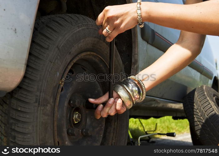 Woman, loosening the bolts on a wheel to change a flat tire