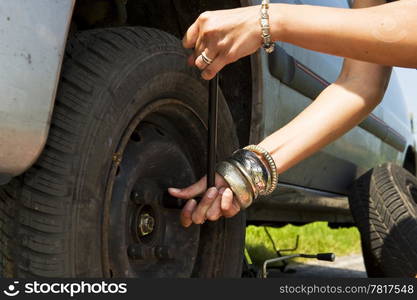 Woman, loosening the bolts on a wheel to change a flat tire