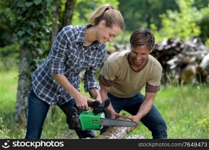 woman lumberjack cuts wood with boyfriend outdoors