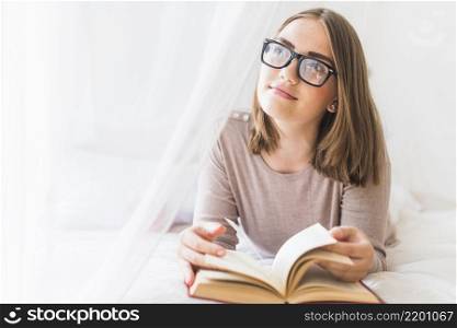 woman lying bed with book daydreaming