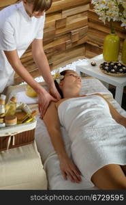 Woman lying down at luxury spa room getting shoulder massage
