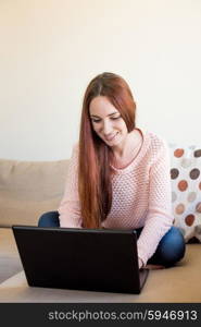 Woman lying down on couch with a laptop