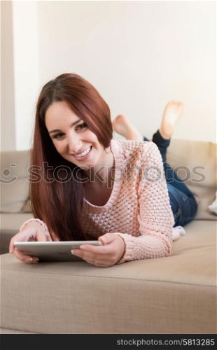 Woman lying down on couch with a tablet