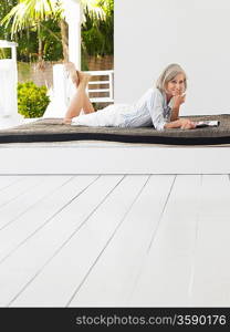 Woman lying down on daybed on verandah portrait