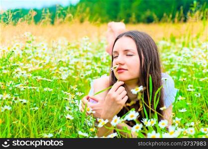 woman lying in a field and smelling a daisy