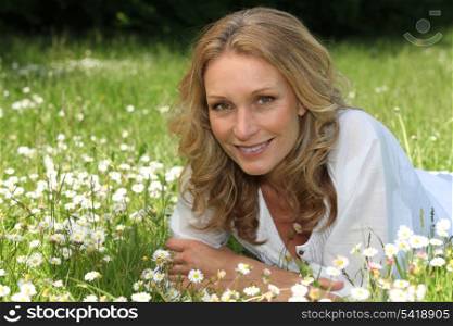 Woman lying in a field of daisies