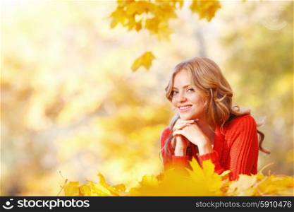 Woman lying in autumn leaves . Beautiful smiling woman lying in autumn maple leaves in park