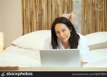 Woman lying in bed with computer