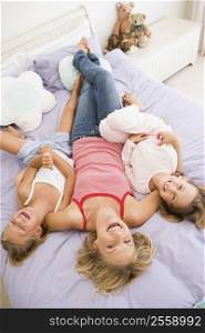 Woman lying in bed with two young girls laughing