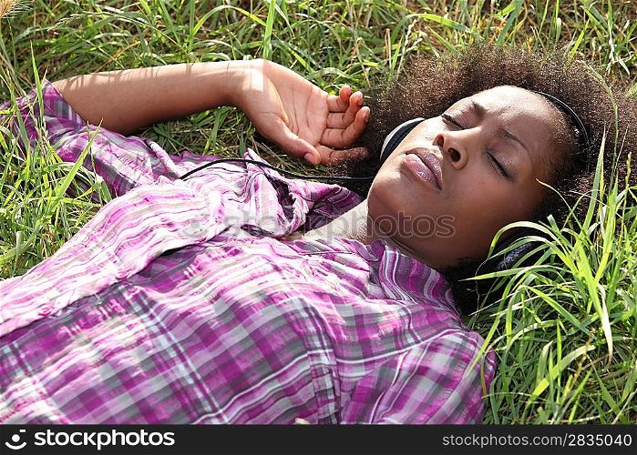 Woman lying in field listening to music