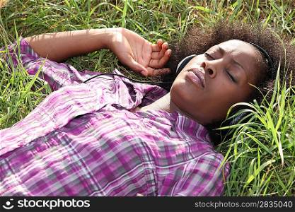 Woman lying in field listening to music