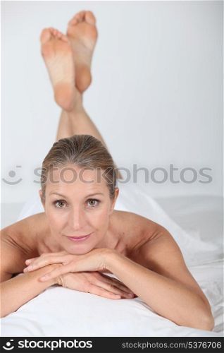 Woman lying naked under a white sheet