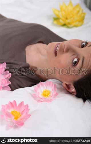 Woman lying on a bed surrounded by flowers