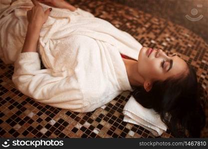 Woman lying on a hot stone, turkish hamam, sauna, side view. Healthcare, skincare and body care. Woman lying on a hot stone, turkish hamam, sauna
