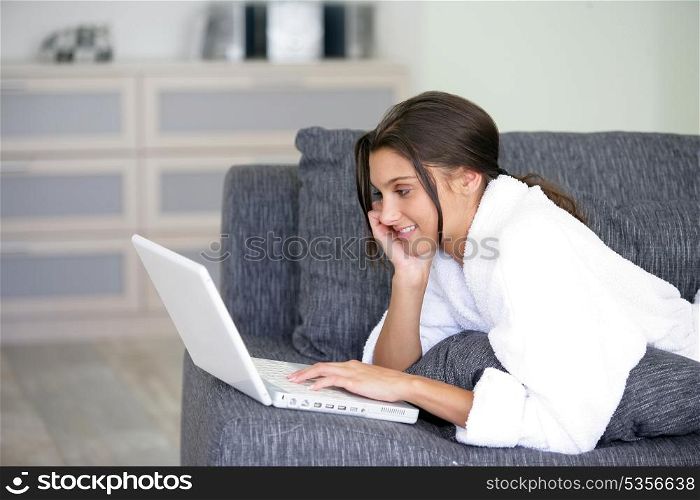 Woman lying on a sofa and using her laptop