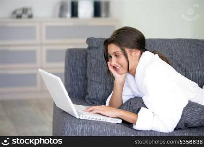 Woman lying on a sofa and using her laptop
