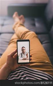 Woman lying on a sofa at home and talking with a doctor online using mobile phone. Telemedicine concept.. Woman lying on a sofa and talking with a doctor online using mobile phone. Telemedicine concept.