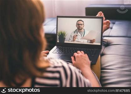 Woman lying on a sofa at home and talking with a doctor online using laptop. Telemedicine concept.. Woman lying on a sofa and talking with a doctor online using laptop. Telemedicine concept.