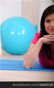 Woman lying on an exercise mat in a gym