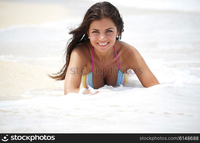 Woman lying on beach. Beautiful smiling woman lying in waves of tropical beach