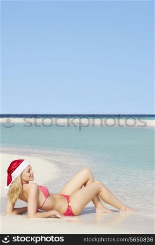 Woman Lying On Beach Wearing Santa Hat