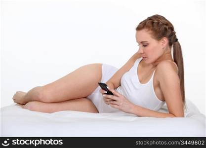 Woman lying on bed with phone