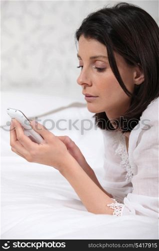 Woman lying on bed with phone