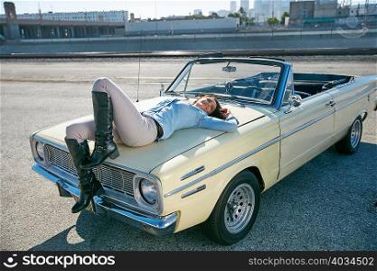 Woman lying on convertible car bonnet, Los Angeles, California, USA