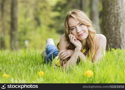Woman lying on dandelions field. Pretty woman lying down on dandelions field happy cheerful girl resting on dandelions meadow, relaxation outdoor in springtime, vacation