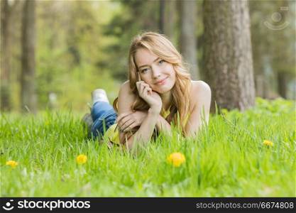 Woman lying on dandelions field. Pretty woman lying down on dandelions field happy cheerful girl resting on dandelions meadow, relaxation outdoor in springtime, vacation