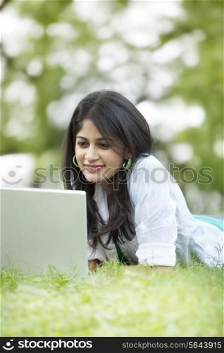 Woman lying on grass and using laptop