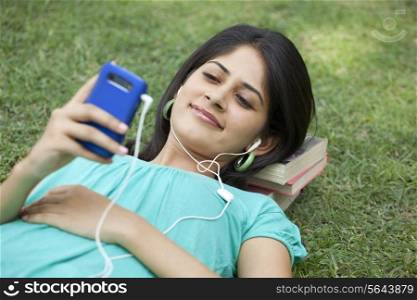 Woman lying on grass listening to music