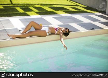Woman lying on her back on pool edge sunbathing in her bikini with a happy smile