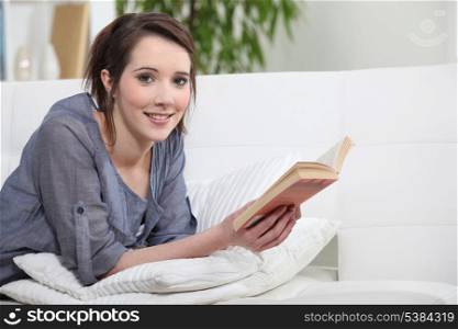 Woman lying on sofa reading