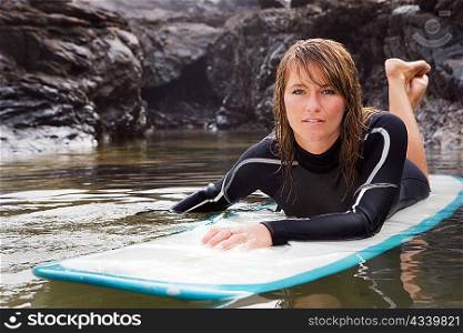 Woman lying on surfboard in the water