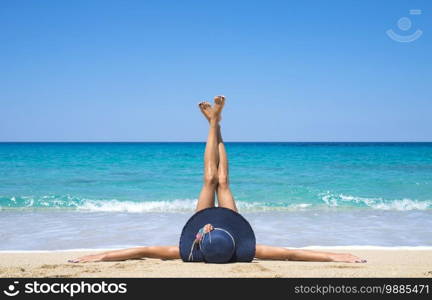 Woman lying on the beach with legs up in the air.