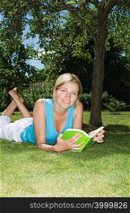 Woman lying on the grass reading a book