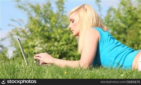 Woman lying on the grass with a laptop