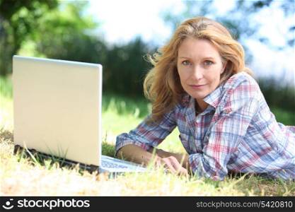 woman lying on the grass with laptop