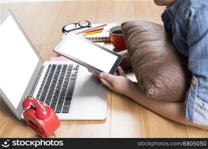 woman lying on wooden floor with computer notebook and tablet