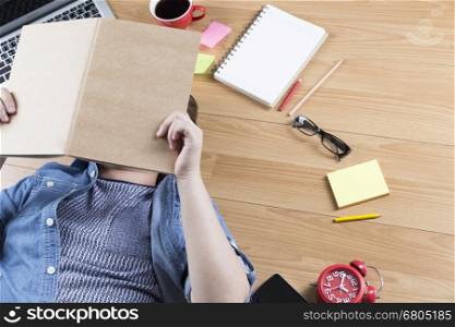 woman lying on wooden floor with mobile phone, notebook and laptop
