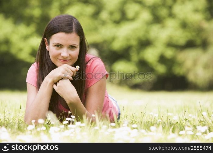 Woman lying outdoors with flower smiling