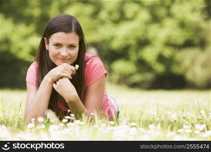 Woman lying outdoors with flower smiling