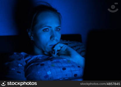 Woman lying with her laptop in night in the living room