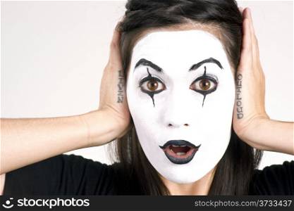Woman made up in white face frames her features with her hands