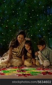 Woman making a rangoli with her kids