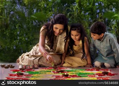 Woman making a rangoli with her kids