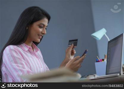 Woman making an online payment through her credit card with a phone in her hand