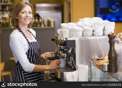 Woman making coffee in restaurant smiling