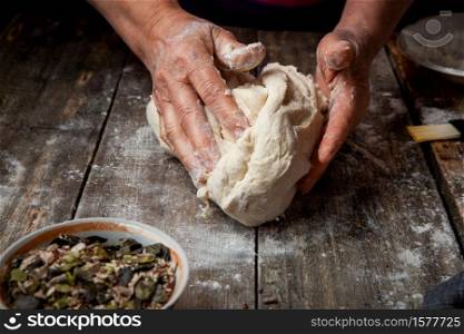 Woman making dough on wooden table close-up.